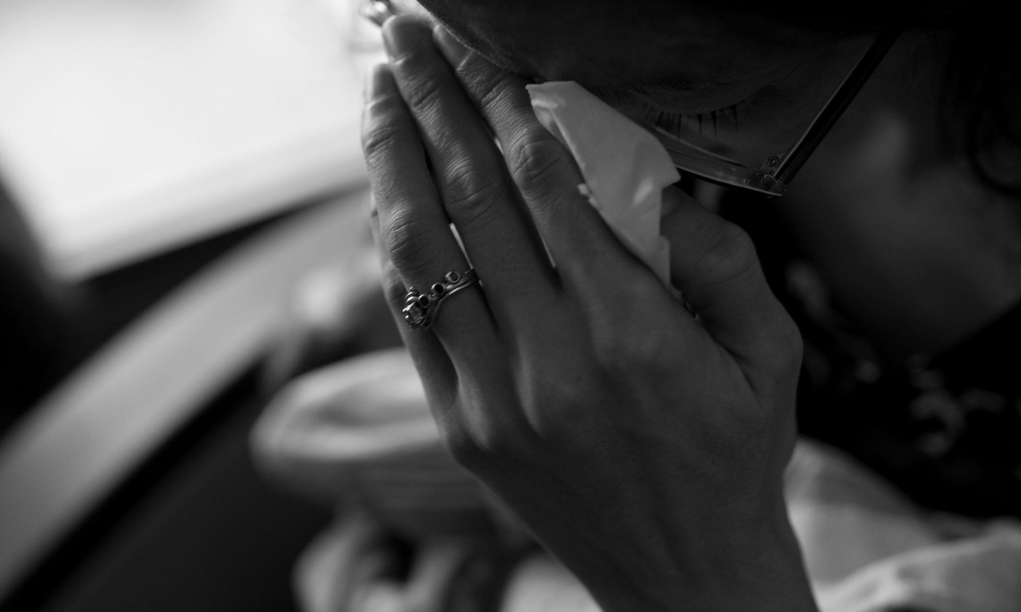 Woman holding her hand to her face, crying into a tissue.